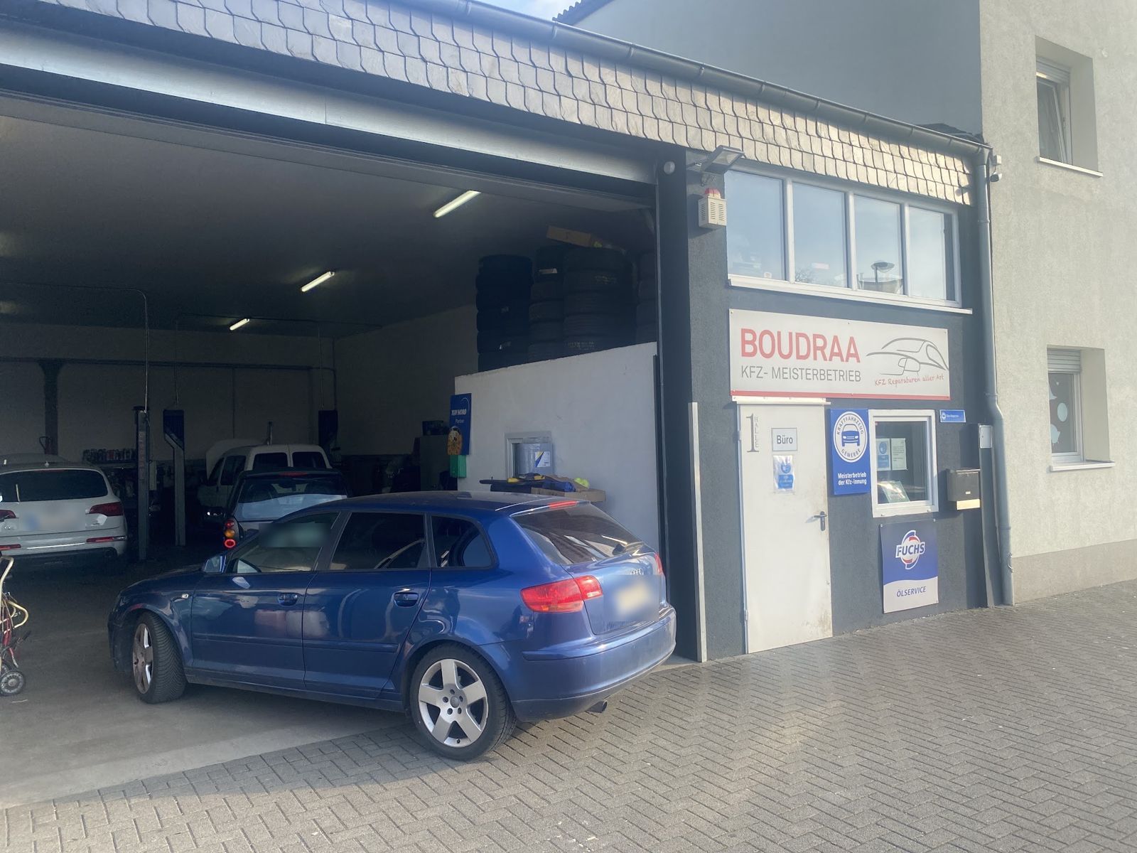 Werkstatt Boudraa in der Weberstraße 100: offenes Hallentor mit Hebebühnen und Reifenregal, daneben das Büro mit dem Schild BOUDRAA Kfz-Meisterbetrieb